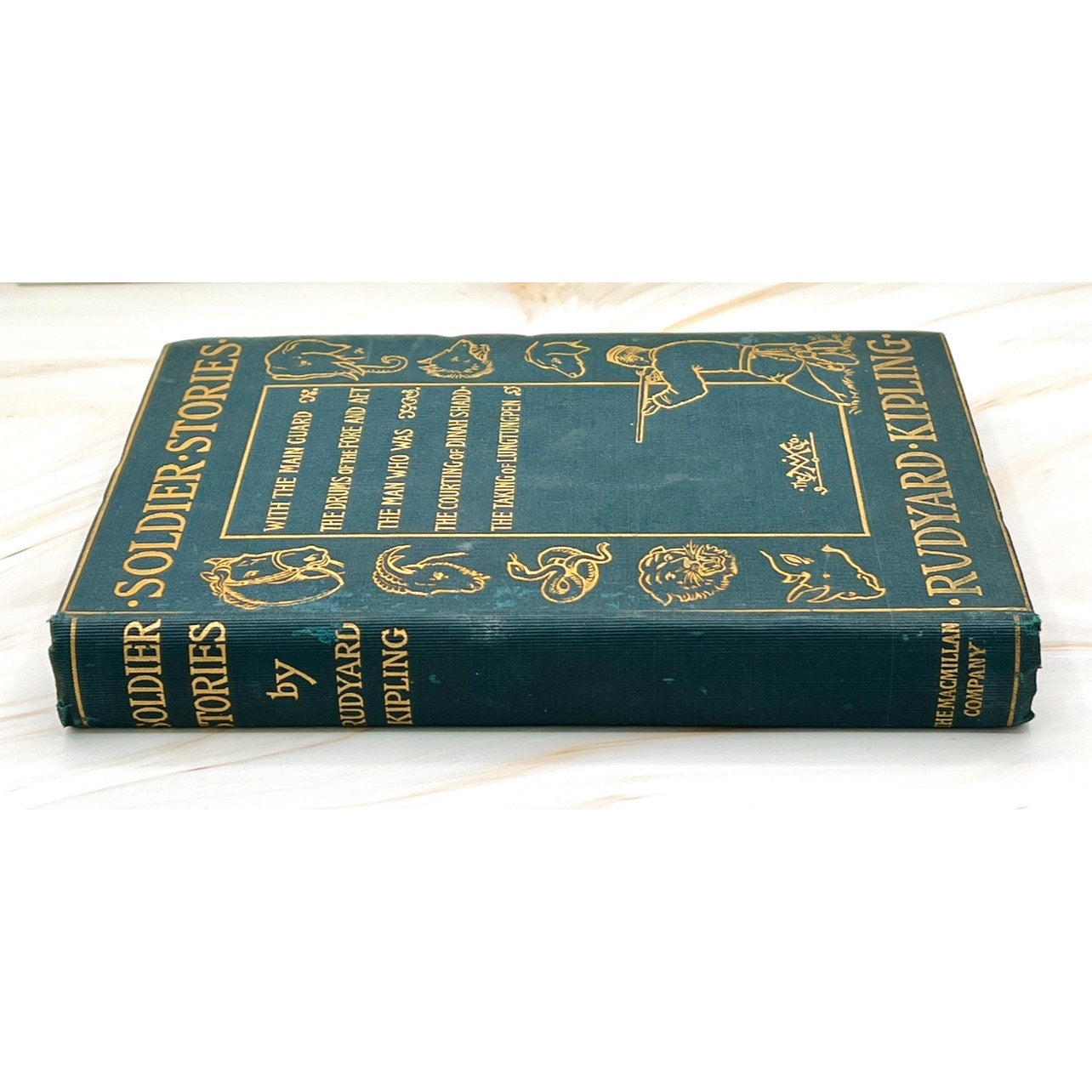 Antique Rudyard Kipling Soldier Stories (1897) hardcover with gilt-stamped soldiers and exotic wildlife on blue-green cover.